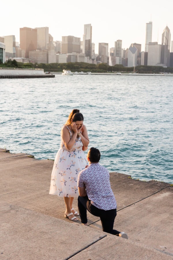 a couple gets engaged at the lakefront in chicago in front of the skyline