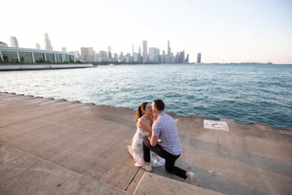 a couple gets engaged at the lakefront in chicago in front of the skyline