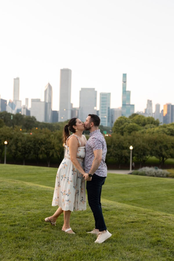 a couple celebrates their Surprise engagement sharing a kiss in front of the chicago skyline at the adler planetarium