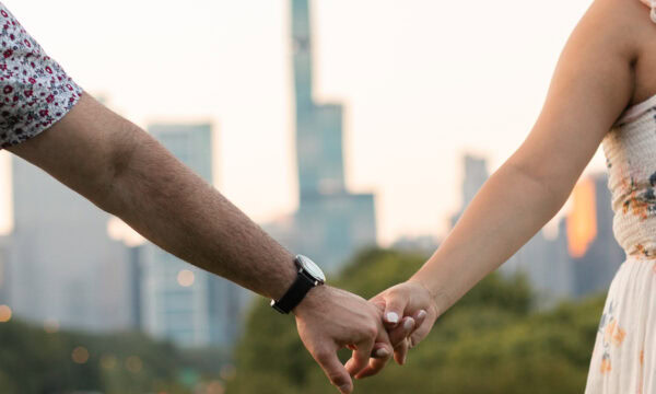 a couple celebrates their Surprise engagement holding hands in front of the chicago skyline at the adler planetarium