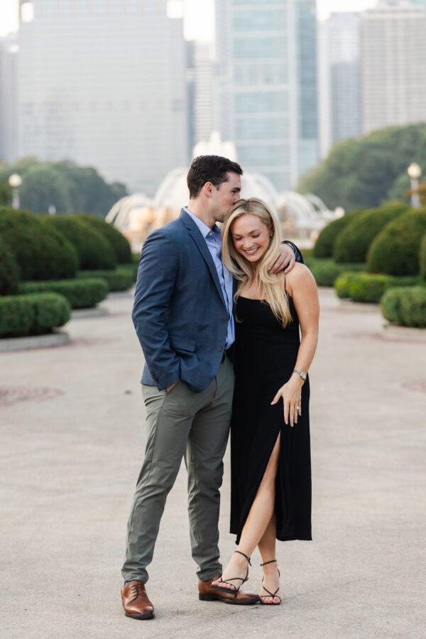 Engaged couple posing for a photo at buckingham fountain Chicago at sunset after their surprise proposal.