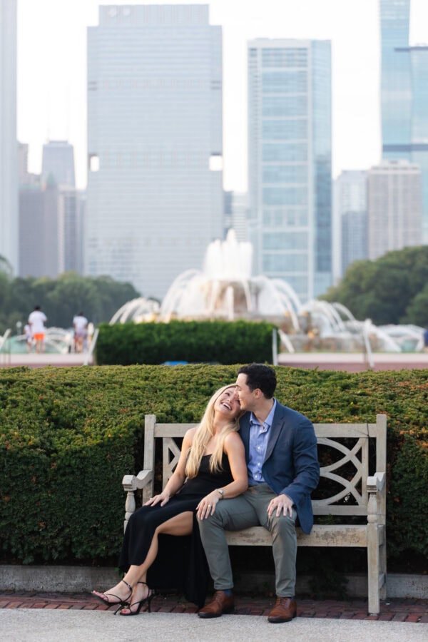 Engaged couple sitting on a bench at buckingham fountain Chicago at sunset after their surprise proposal.