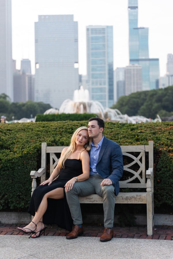 Engaged couple sitting on a bench at buckingham fountain Chicago at sunset after their surprise proposal.