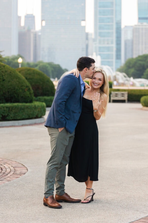 Engaged couple showing off the ring at buckingham fountain Chicago at sunset after their surprise proposal.