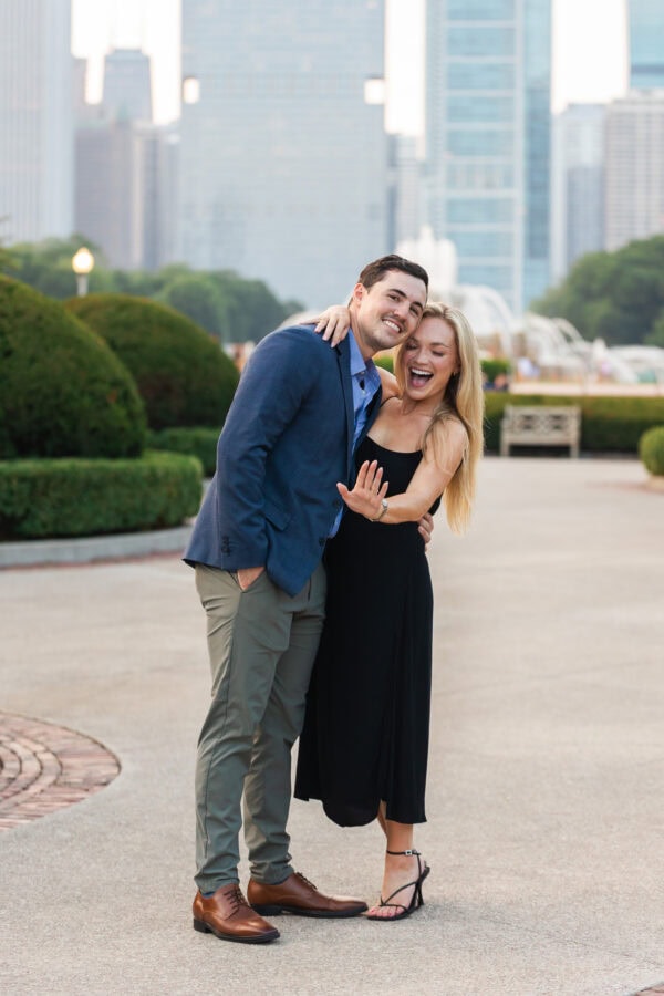 Engaged couple showing off the ring at buckingham fountain Chicago at sunset after their surprise proposal.