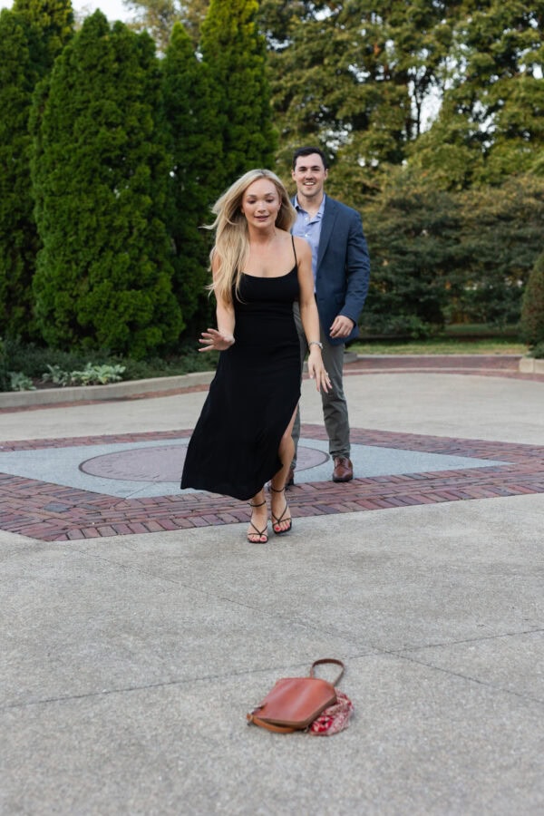 Woman runs forward in excitement, dropping her purse as partner follows, moments after a surprise proposal in downtown chicago