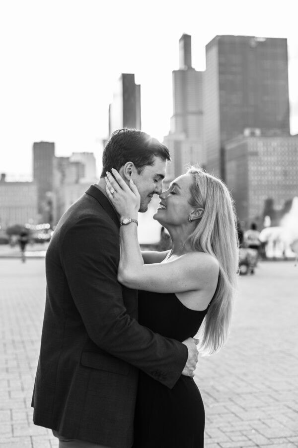 Engaged touching noses at buckingham fountain in Chicago after their surprise proposal.