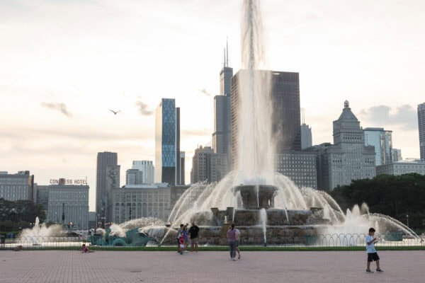 Couple near Buckingham Fountain with Chicago skyline at sunset, capturing a scenic moment from a surprise proposal