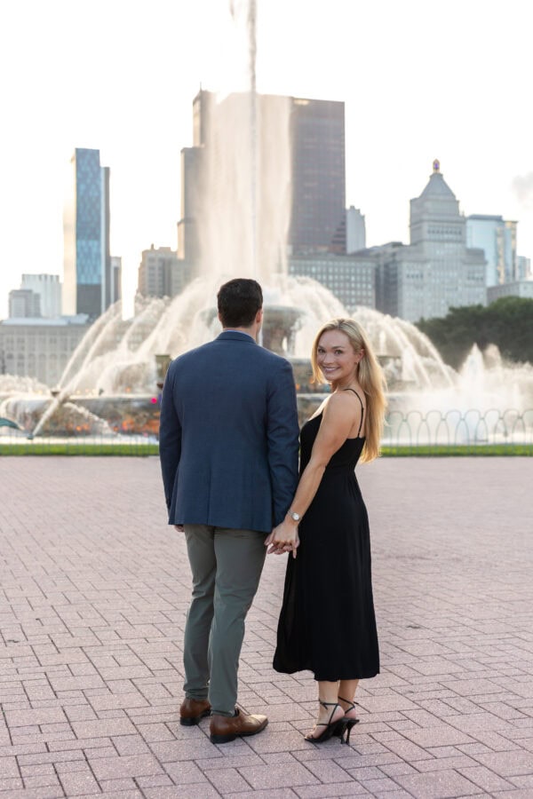 Engaged couple walking at buckingham fountain Chicago at sunset after their surprise proposal.