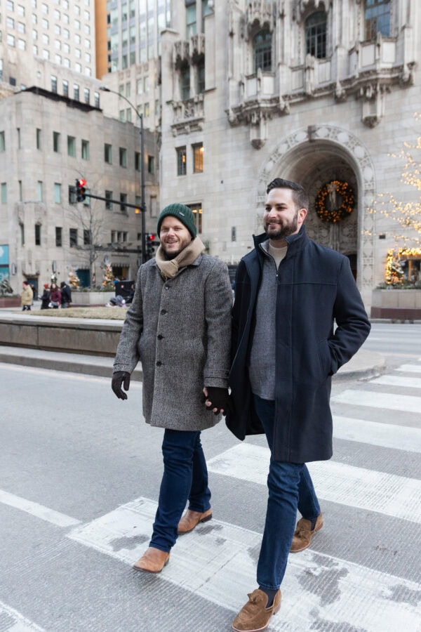 A same sex couple holds hands and walk across michigan ave during a chicago winter