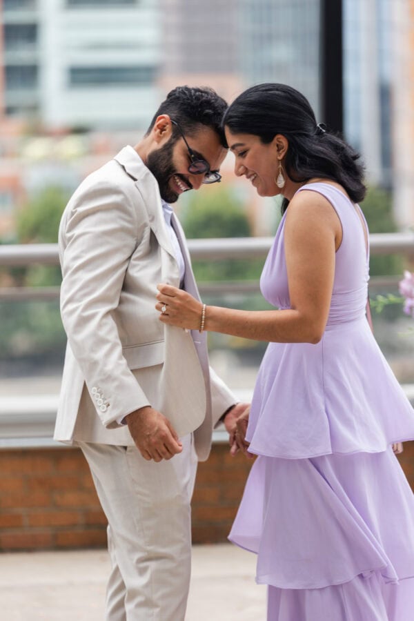 a newly engaged woman looks inside her fiance's suit jacket to read a custom inscription as they both smile