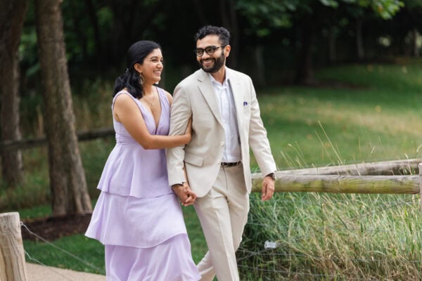 a newly engaged couple holding hands take a walk in a chicago garden on a summer day