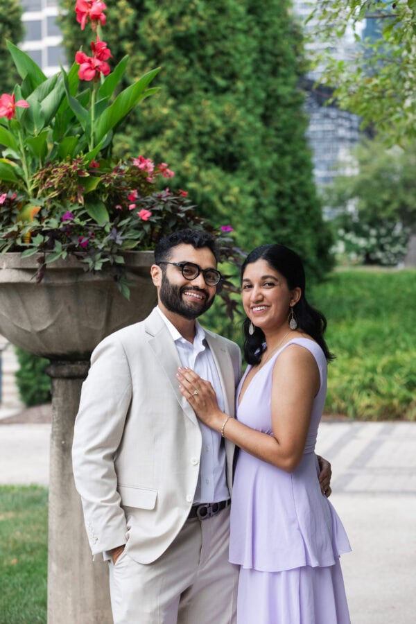 a newly engaged couple pose for a photo in a chicago garden on a summer day