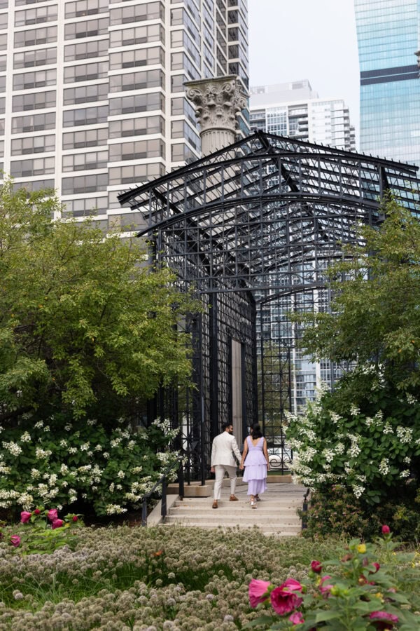 a newly engaged couple holding hands take a walk in a chicago garden on a summer day