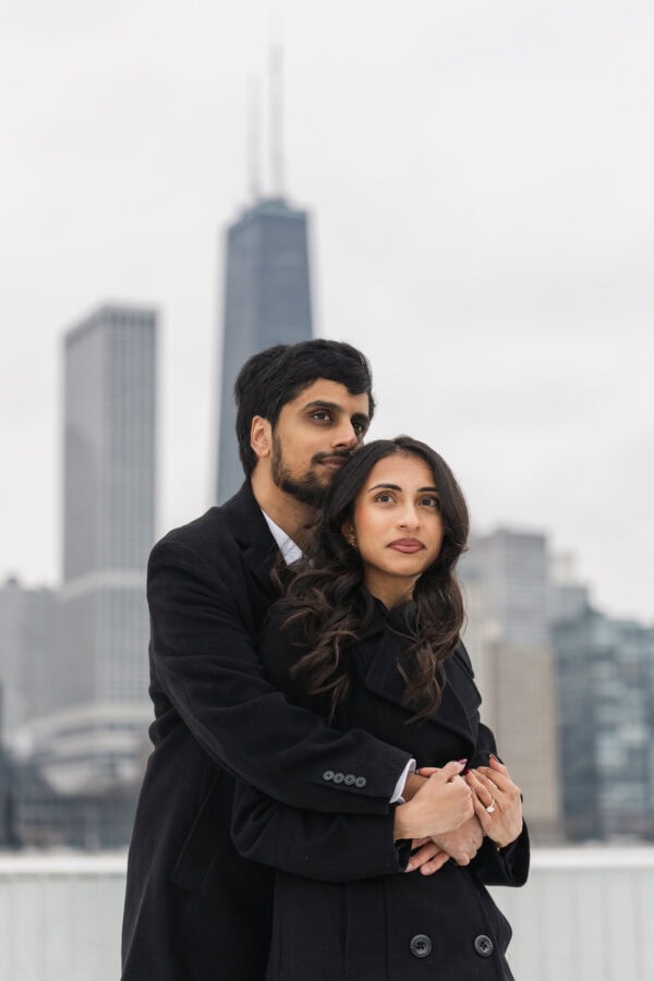 a couple shares a hug while posing for engagement photos at Olive Park in Chicago on a winter day