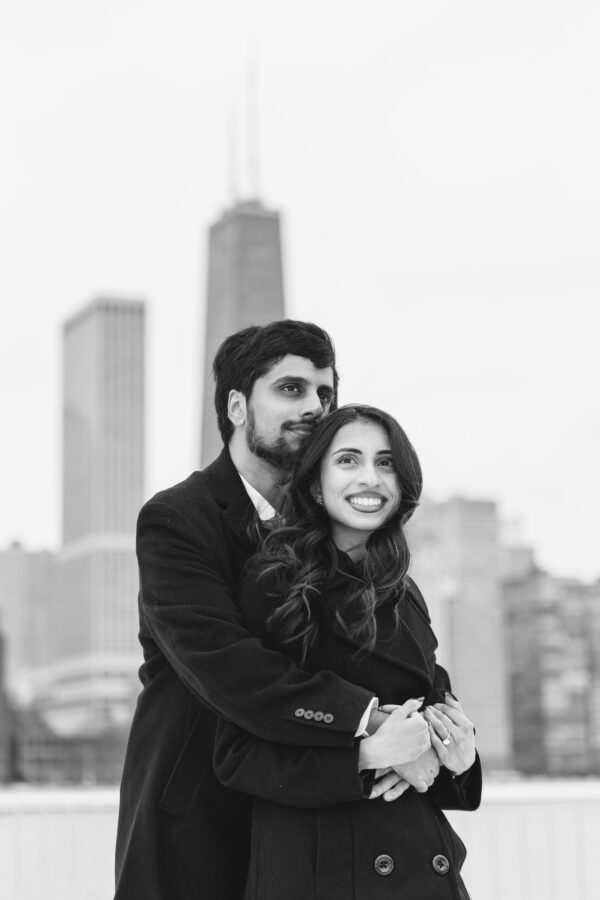 a couple shares a hug while posing for engagement photos at Olive Park in Chicago on a winter day