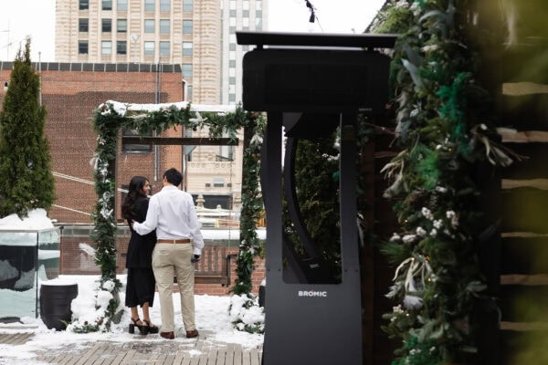 Man and woman share a conversation on a chicago rooftop surrounded by snowy greenery