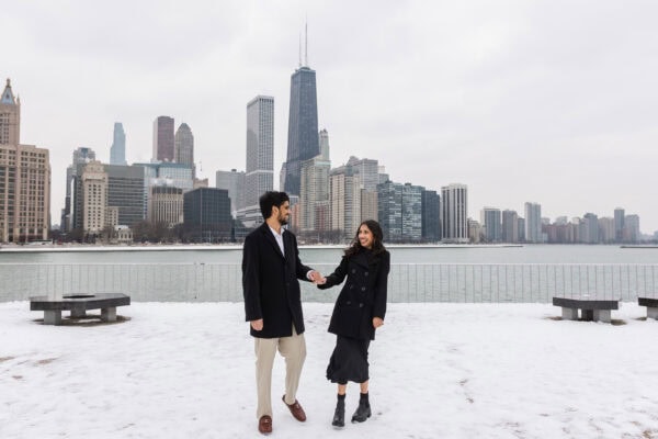 a couple posing for engagement photos at Olive Park in in front of the Chicago Skyline on a winter day