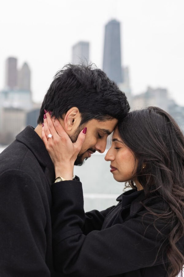 a couple posing for engagement photos at Olive Park in in front of the Chicago Skyline on a winter day