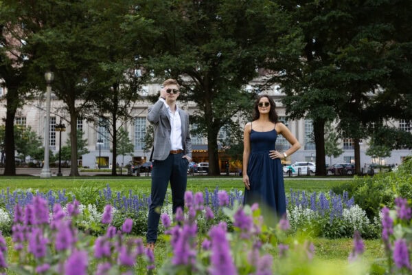 a well dressed couple stands in a garden on michigan ave in chicago posing for a photo with sunglasses on