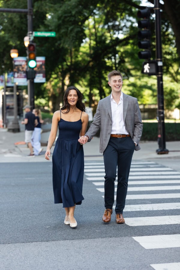 a well dressed couple crosses the street while holding hands on michigan avenue in chicago