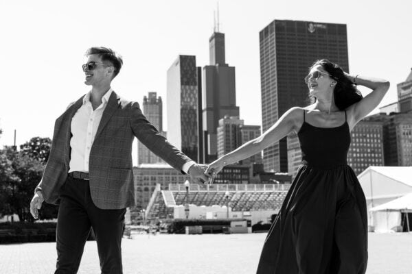 a man and women walk hand in hand in front of the chicago skyline