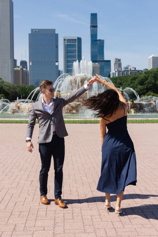 a man and woman pose for a photo by spinning in front of chicago's buckingham fountain