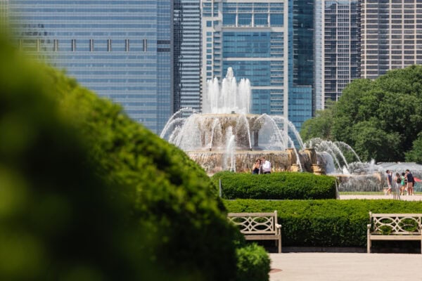 A couple stops to take a photos in front of the chicago buckingham fountain on a summer day