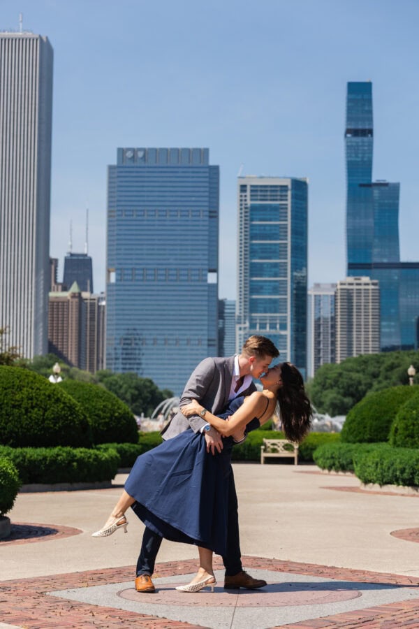 a man is dipping his girlfriend fora kiss while posing for a photo in front of the chicago skyline