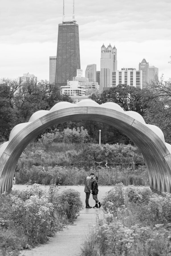 A newly engaged couple shares a kiss in front of the chicago skyline in Lincoln Park's Honeycomb