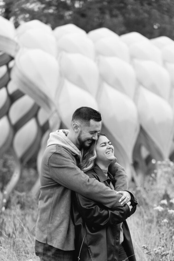 A engaged couple share a near hug in front of the honeycomb pavilion in Chicago's Lincoln Park