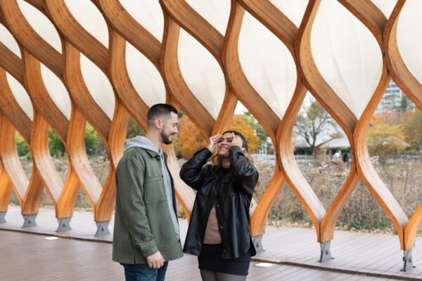 a couple shares a look of shock after the groom to be proposed to his partner in the lincoln park peoples gas pavillion