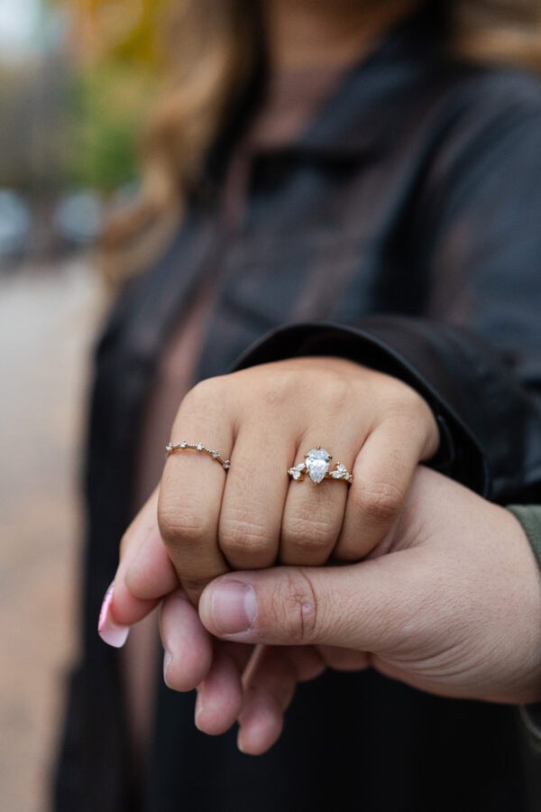 A close up shot of a woman's hand wearing an engagement ring