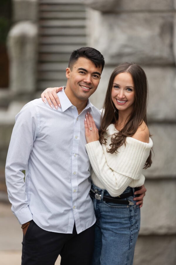 Couple poses for a photo during an engagement session looking directly into the camera smiling