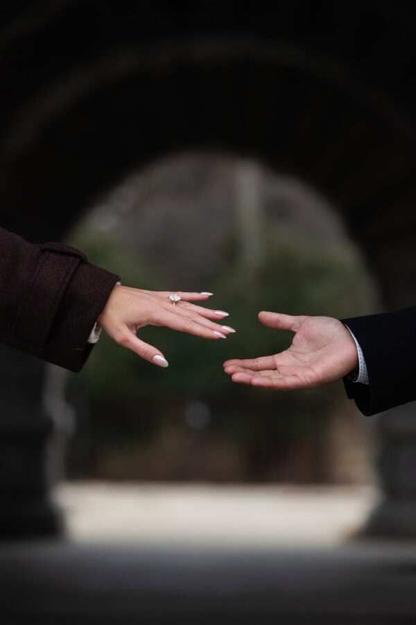 close shot of the hands of engaged couple reaching for each other displaying an engagement ring