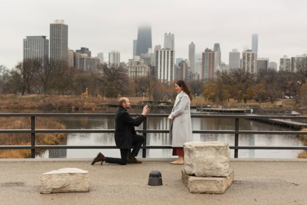 a man is down on one knee proposing to his girlfriend at Lincoln park zoo in Chicago