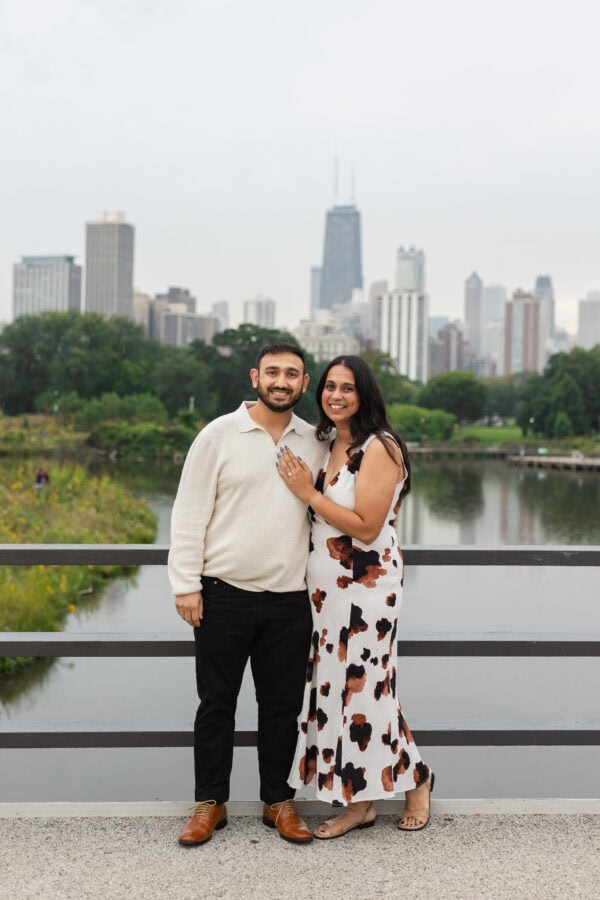 a newly engaged couple poses for a photo in front of the chicago skyline at lincoln park zoo