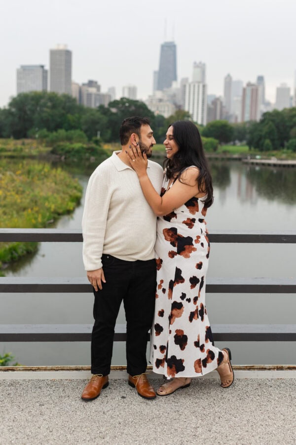a newly engaged couple poses for a photo in front of the chicago skyline at lincoln park zoo