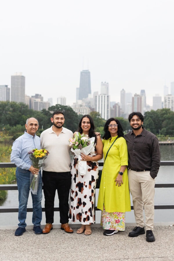 a family poses for a group photo in front of the chicago skyline, while holding bouquets of flowers