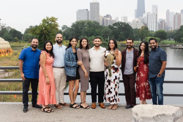 a family poses for a group photo in front of the chicago skyline, while holding bouquets of flowers