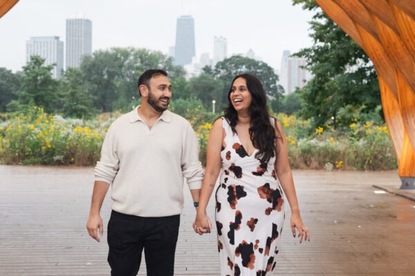 a couple holding hands walks under the peoples gas pavilion in chicago's lincoln park zoo