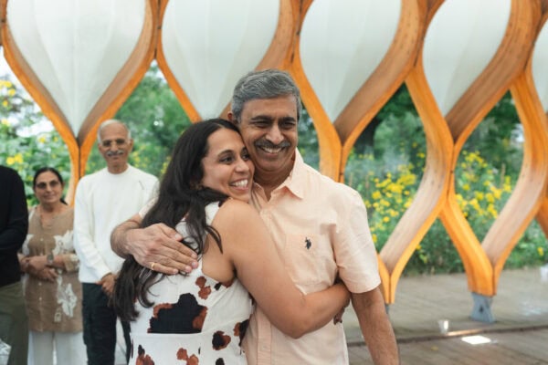 a father bugs his daughter who just got engaged, both smiling