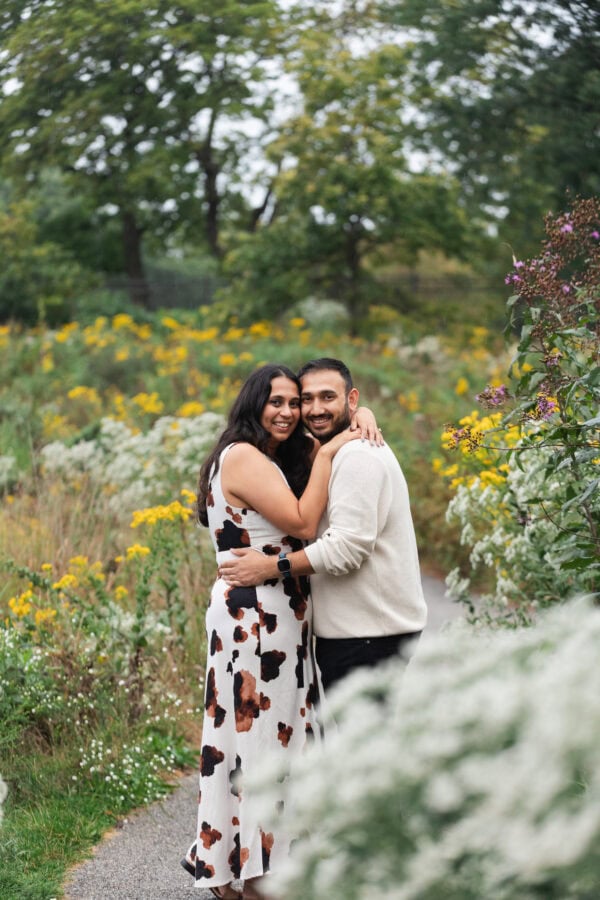 a newly engaged couple poses for a photoin a field of flowers at lincoln park zoo