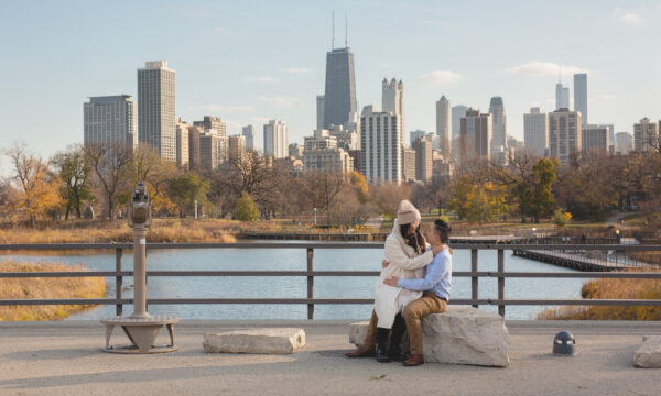 a man and a women sit on a rock posing for a photo on the lincoln park zoo south pond bridge