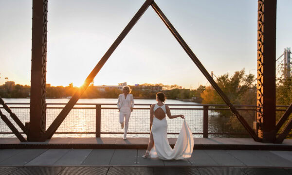 The brides pose for a photo on a bridge at sunset