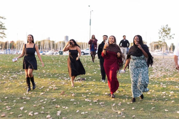 friends of a couple who just got engaged are running across montrose harbor in chicago to congratulate them