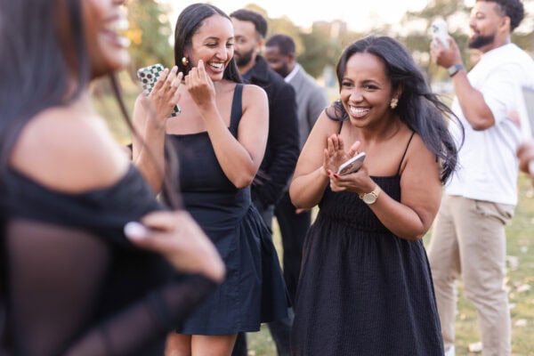 two women are clapping and smiling while looking at their newly engage friend