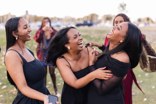 3 women hug and laugh as they celebrate their friend having just been proposed to