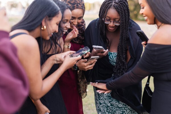 4 women take a photo of their friends hand that is displaying her brand new diamond engagement ring