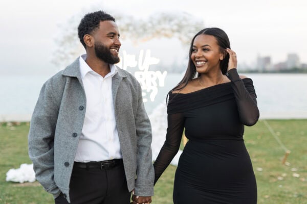 a newly engaged couple poses for a photo in Chicago at the lakefront at montrose harbor